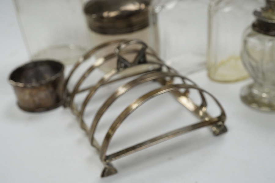 An Art Deco silver five bar toast rack by Charles S. Green & Co Ltd, Birmingham, 1935, 9cm, a silver napkin ring and six assorted silver topped glass toilet bottles. Condition - poor to fair